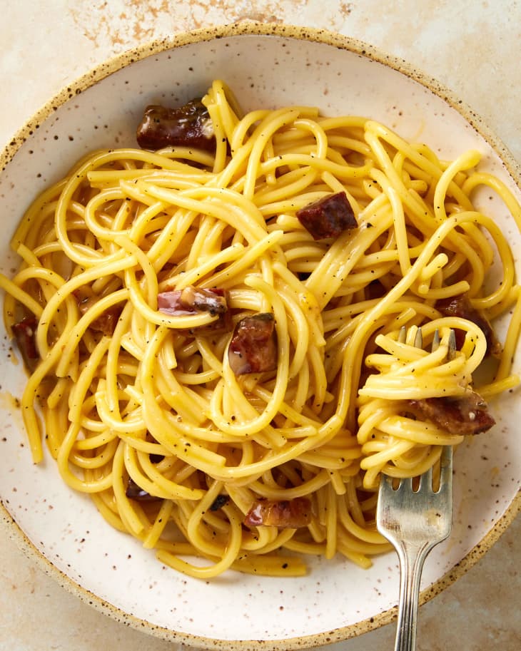 Overhead shot of carbonara in a bowl with a fork resting in the bottom right of the bowl.