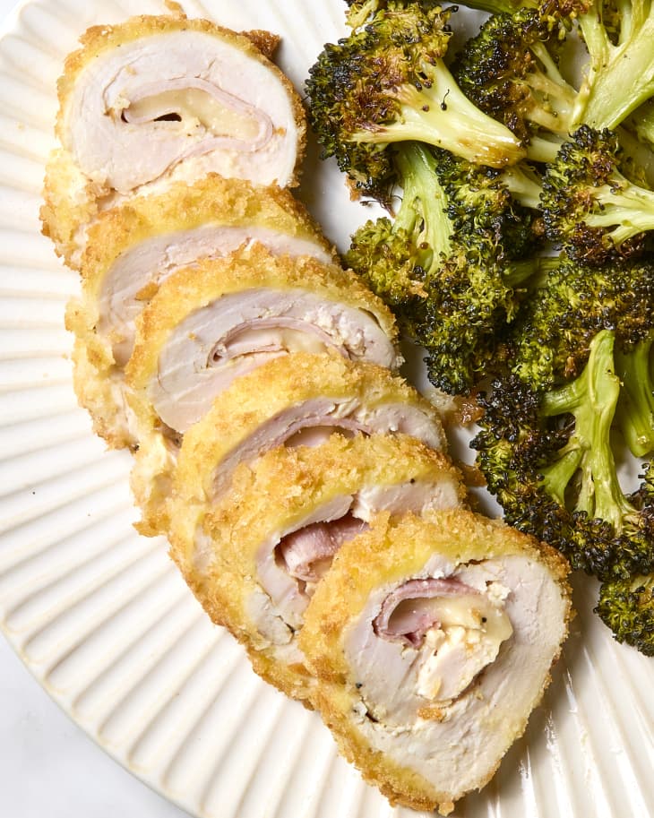 overhead shot of chicken cordon bleu sliced on a white scalloped plate with roasted broccoli.