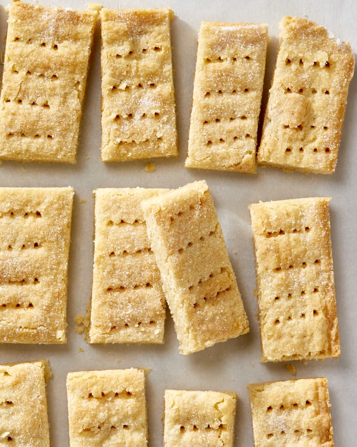 Overhead shot of a sheet of shortbread cookies, with one of the center ones resting on the cookie to the left of it.