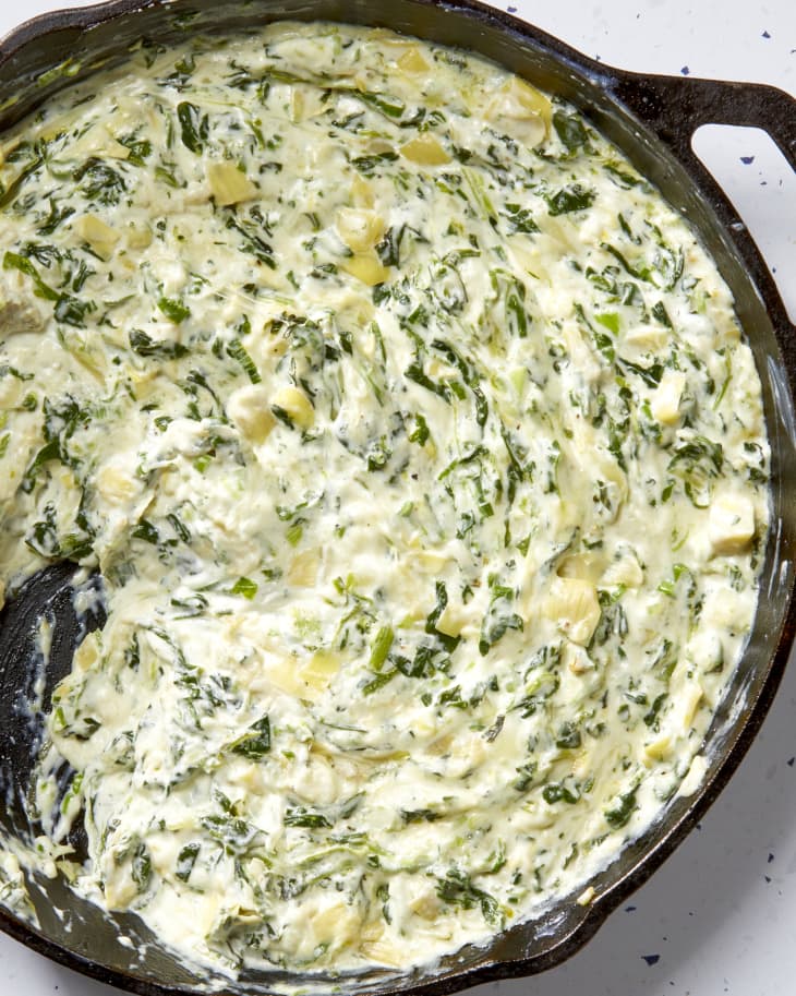 Overhead shot of spinach artichoke dip in a cast iron pan, unbaked.