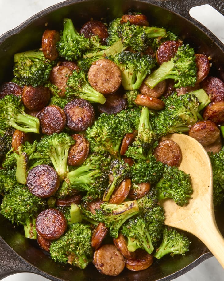 Sausage slices and broccoli sautéed with Cajun seasoning in a cast iron skillet.