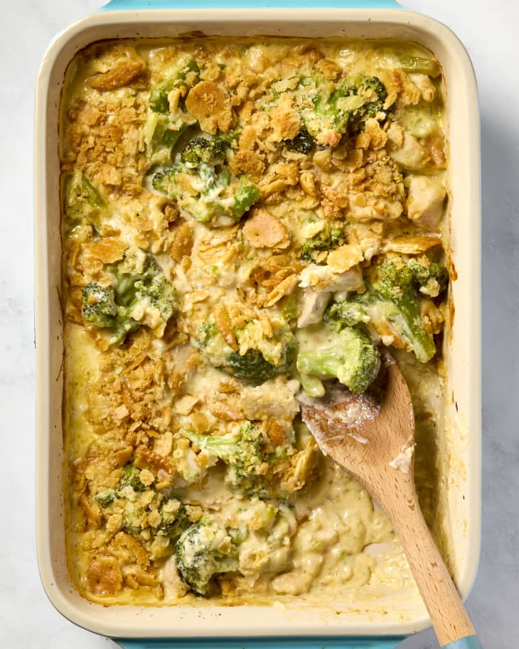 overhead shot of the chicken divan in a baking dish, with a big scoop taken out of it by a large wooden spoon.