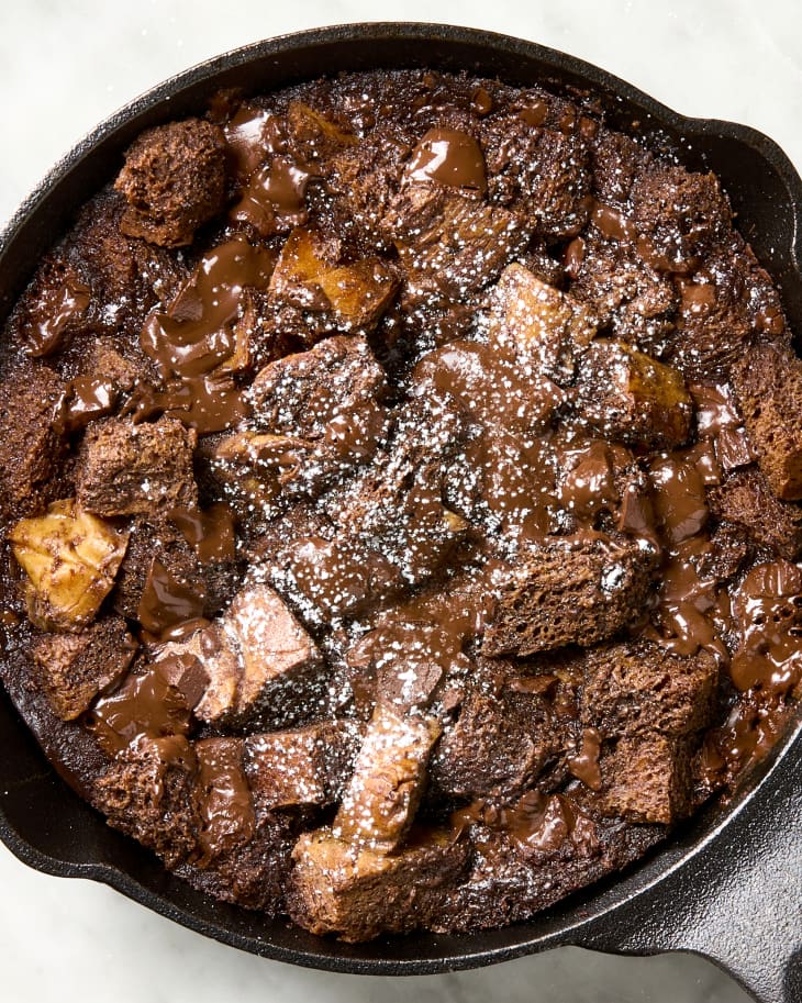 overhead shot of chocolate bread pudding in a cast iron skillet, topped with powdered sugar.