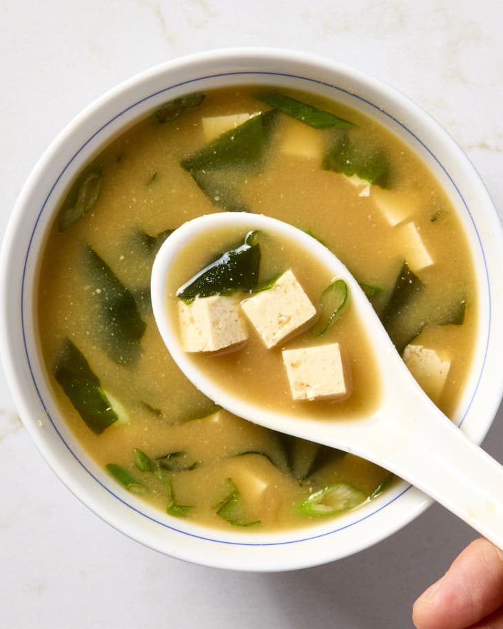 A spoon above a bowl of miso soup.