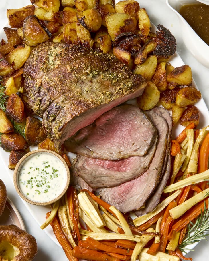 overhead shot of a serving platter with a full roast beef, roasted carrots and crispy potatoes.