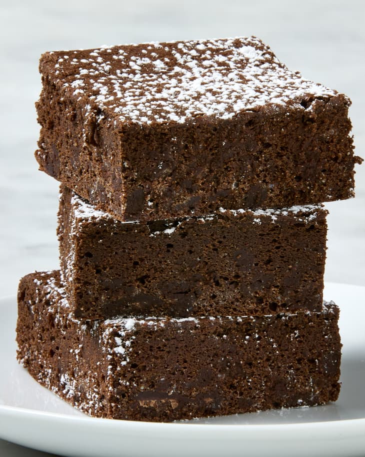 Photo of a stack of 3 brownies topped with powdered sugar.