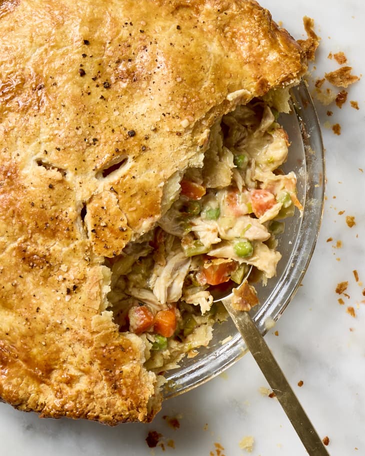 overhead shot of a chicken pot pie with a large scoop taken from it, with a serving spoon resting in the dish.
