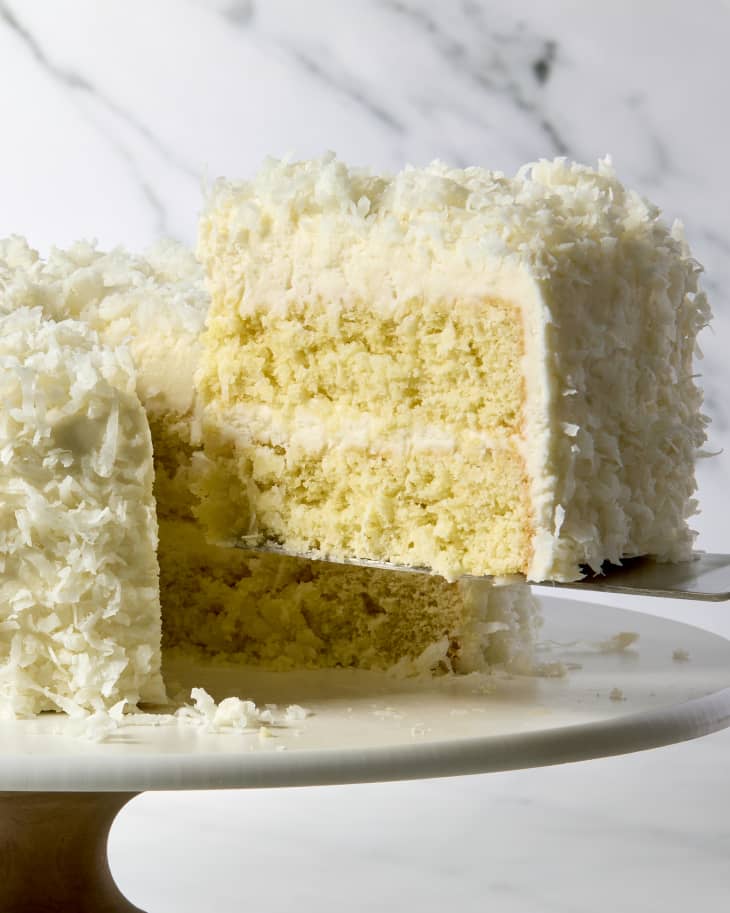 a slice being taken from a whole coconut cake.