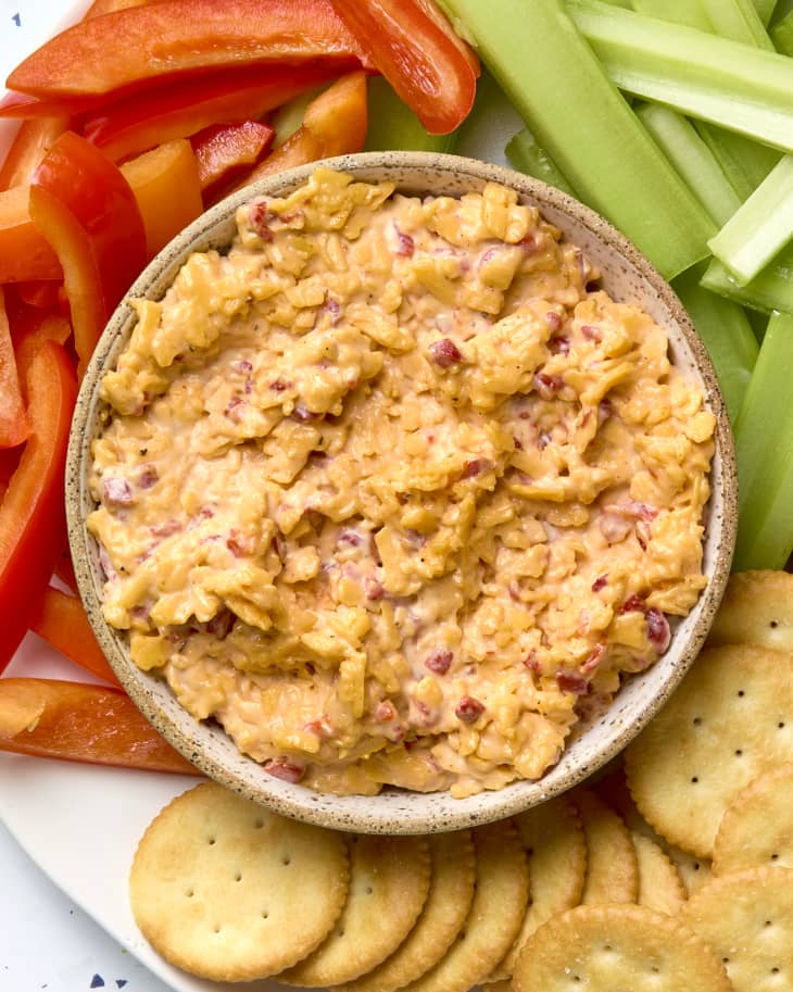 overhead shot of pimento cheese in a small bowl on a plate with fresh veggies and ritz crackers.