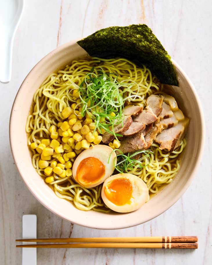 chopsticks and soup spoon tightly placed near pink bowl of shoyu ramen