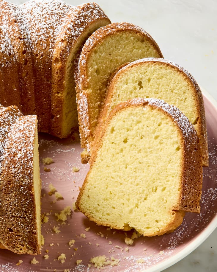 angled shot of a sour cream pound cake with a few slices cut and leaning against each other.