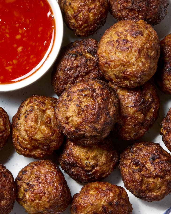 overhead shot of meatballs piled on a plate with a small bowl of sweet chili sauce.