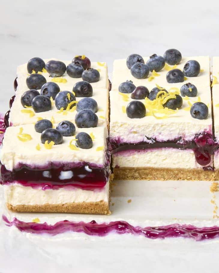 angled shot of lemon blueberry delight pieces, topped with fresh blueberries and lemon, with one missing in the front.