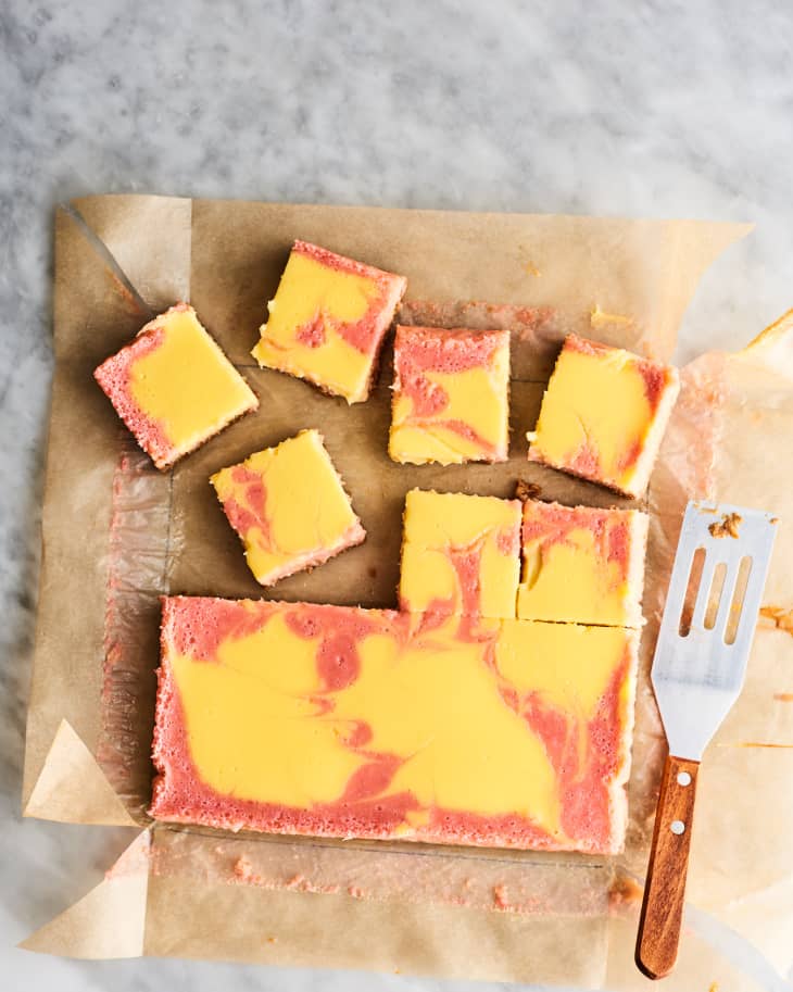 swirled rhubarb cheesecake bars cut into squares on parchment paper