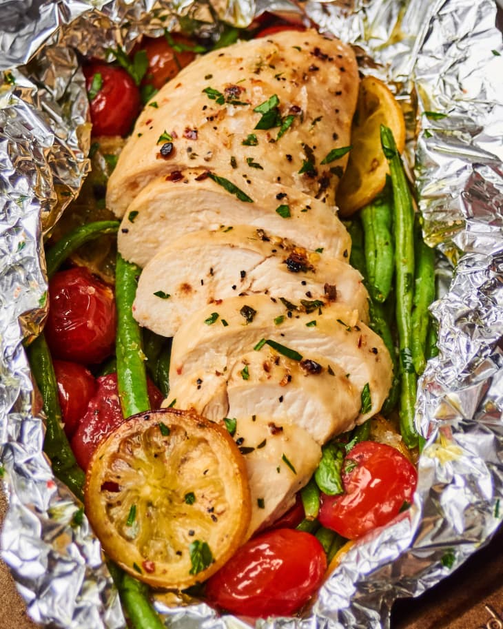 Chicken, green beans, tomatoes, and lemon cooked in a foil packet
