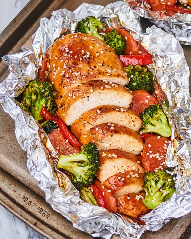 Chicken, broccoli, and carrots cooked in a foil packet topped with sesame seeds