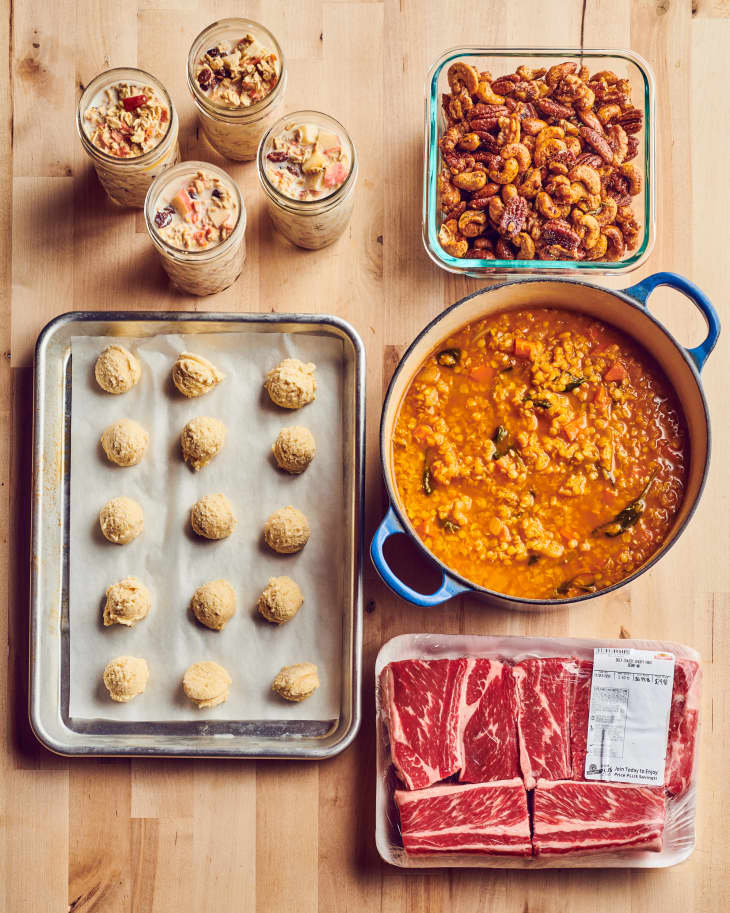 Power hour meal prep from clockwise top right: Spiced nuts in glass container, Lentil soup in Dutch oven, Short ribs on butcher paper, Frozen gougeres on parchment-lined baking sheet, 4 Mason jars of Morning Glory Overnight Oats