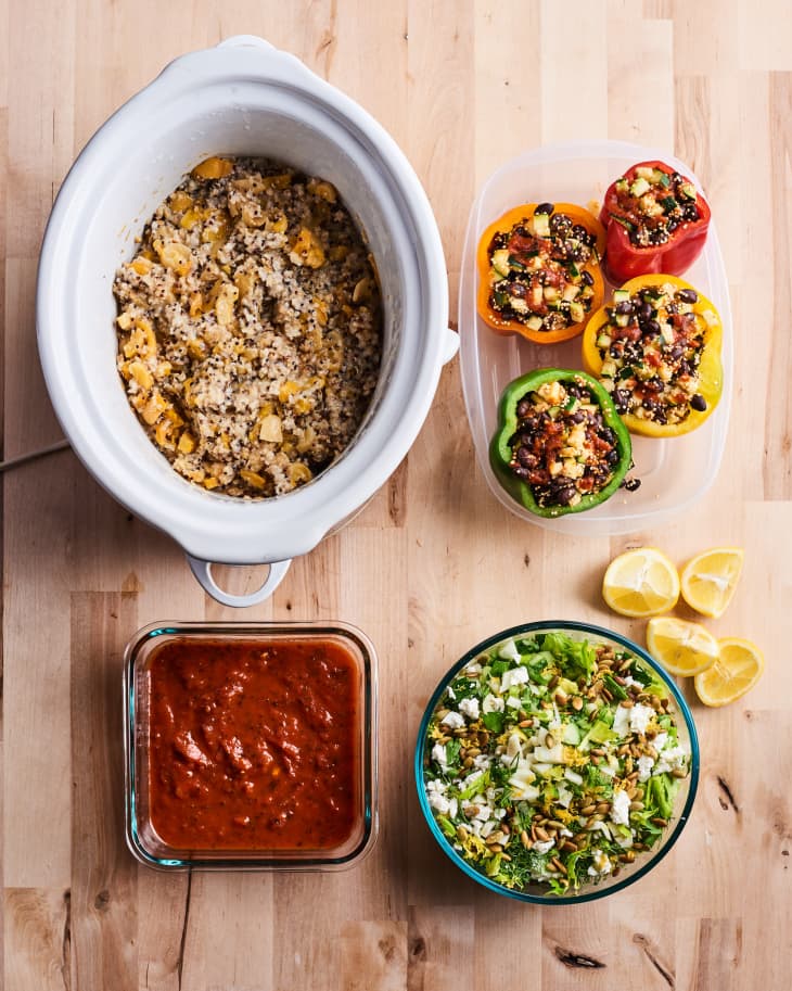 a slow cooker, stuffed pepper, salad, and chili sit in separate containers on a table