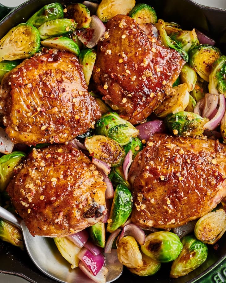 finished chicken sits on top of sprouts and onion in cast iron skillet