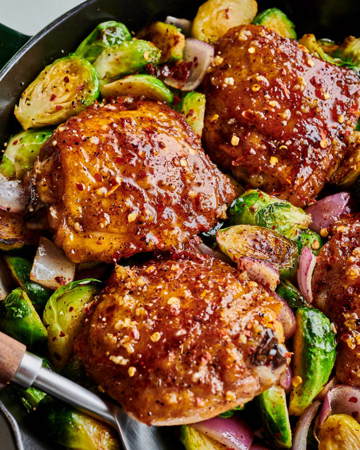 finished chicken sits on top of sprouts and onion in cast iron skillet