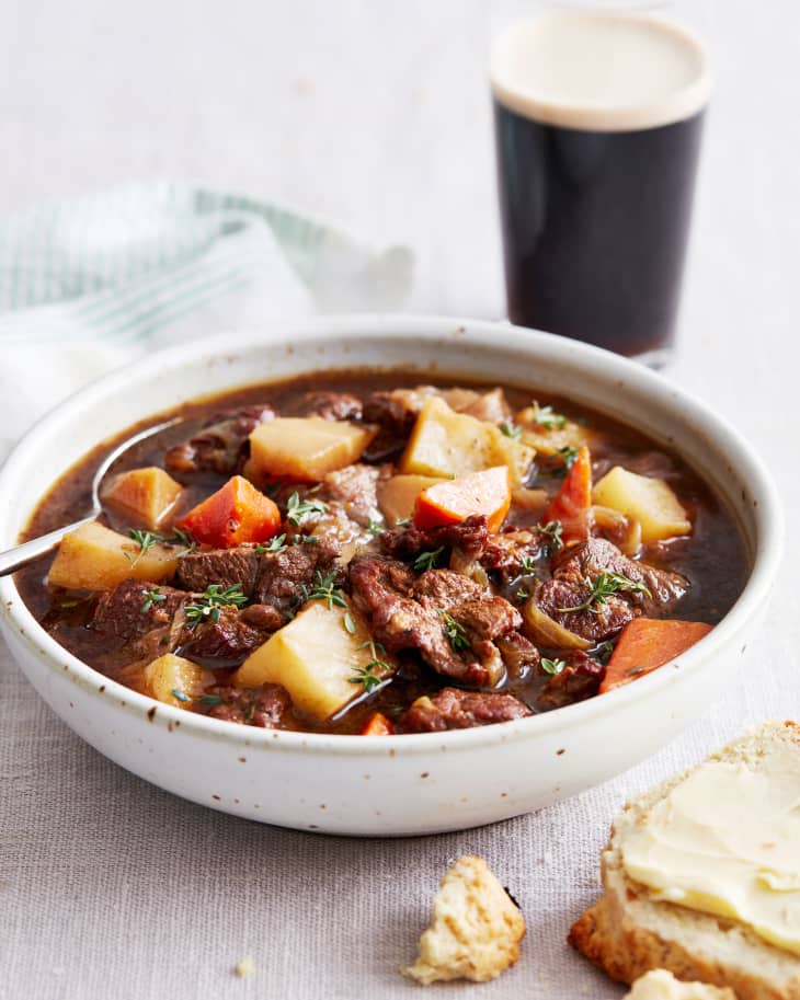 lamb stew sits in a bowl next to a stout beer
