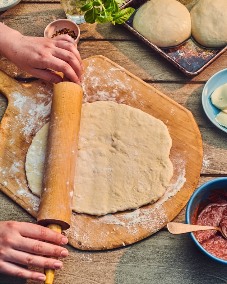 pizza dough being rolled out on a pizza spoon
