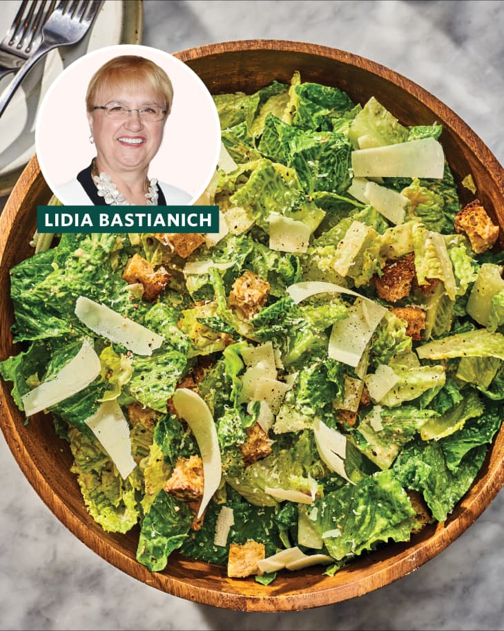Caesar salad with romaine lettuce, croutons, and shaved parmesan in a wooden bowl, featuring Lidia Bastianich.