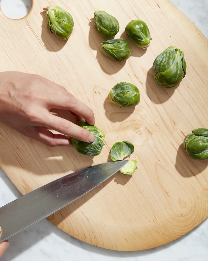 brussels sprouts being chopped on cutting board