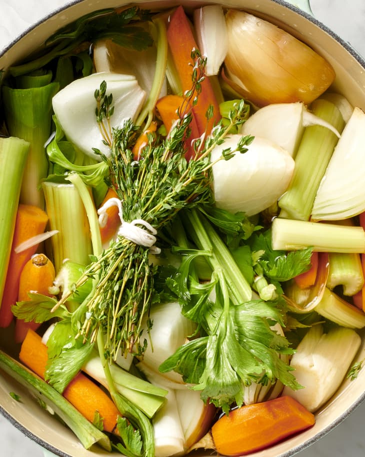 Overhead view of vegetables and herb bundle in a light blue pot.