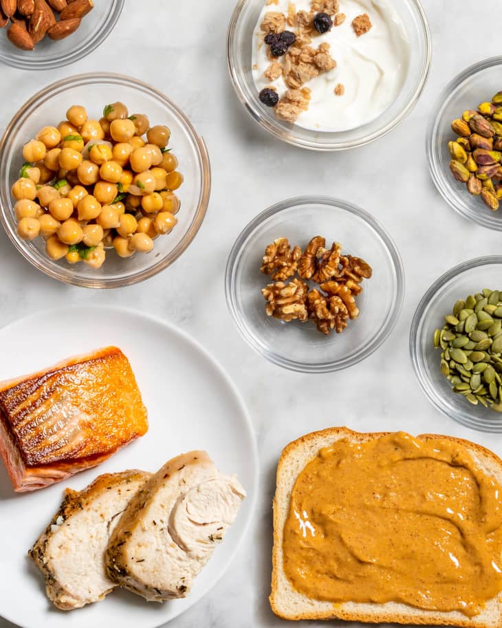 overhead shot of 3 oz servings of different proteins: chickpeas, almonds, greek yogurt, walnuts, pistachios, pepitas, salmon, chicken breast, and peanut butter on toast