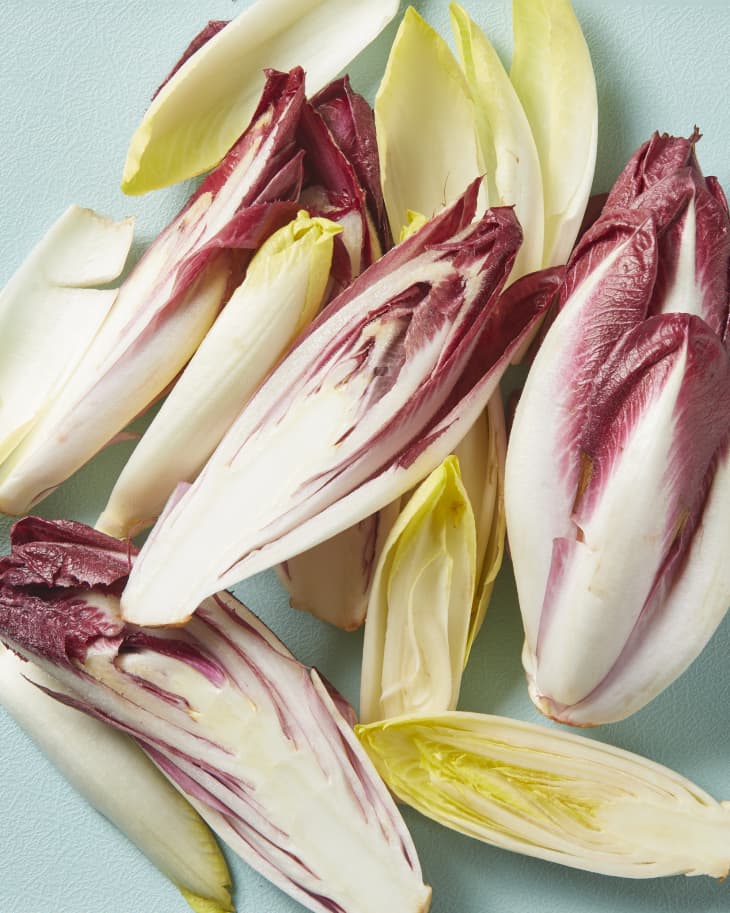 Overhead view of green and red endives on a blue cutting board.