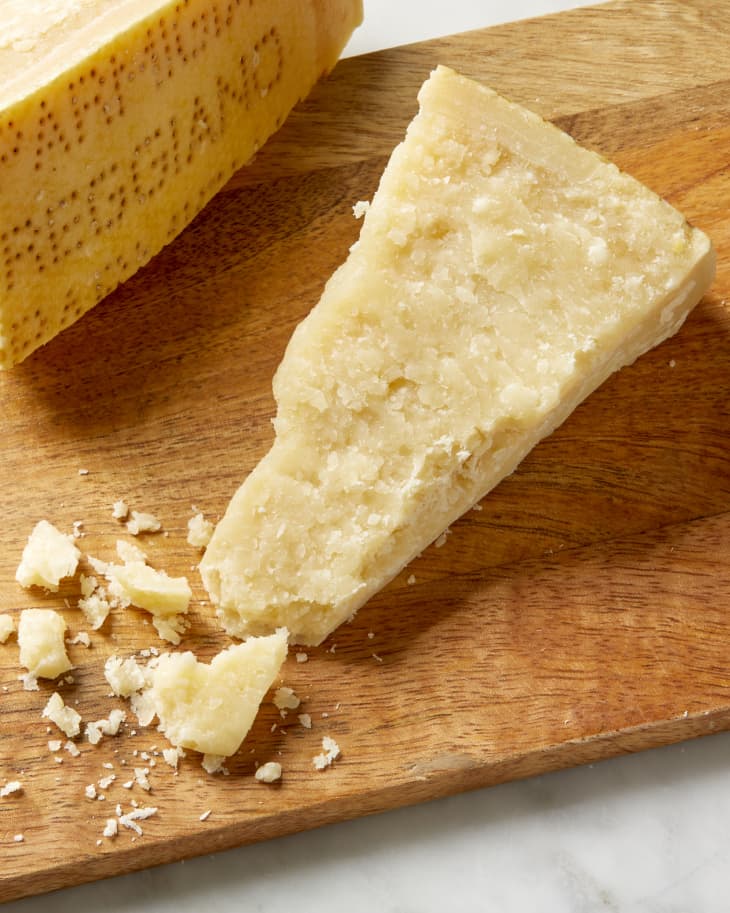 Overhead shot of a small wedge of parmigiano reggiano, on a wooden cutting board.