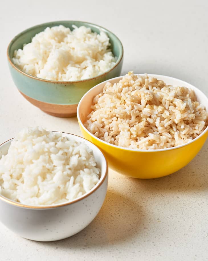 Three bowls, each filled with a different type of cooked rice: long-grain white, brown, and jasmine