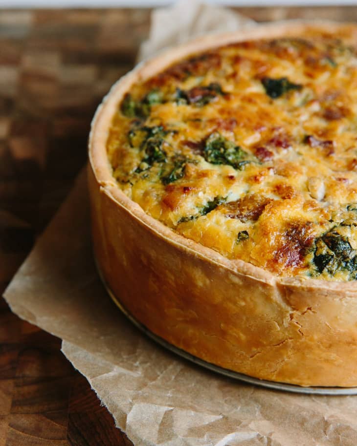 Deep-dish Quiche lorraine with Swiss chard and bacon set on a parchment paper