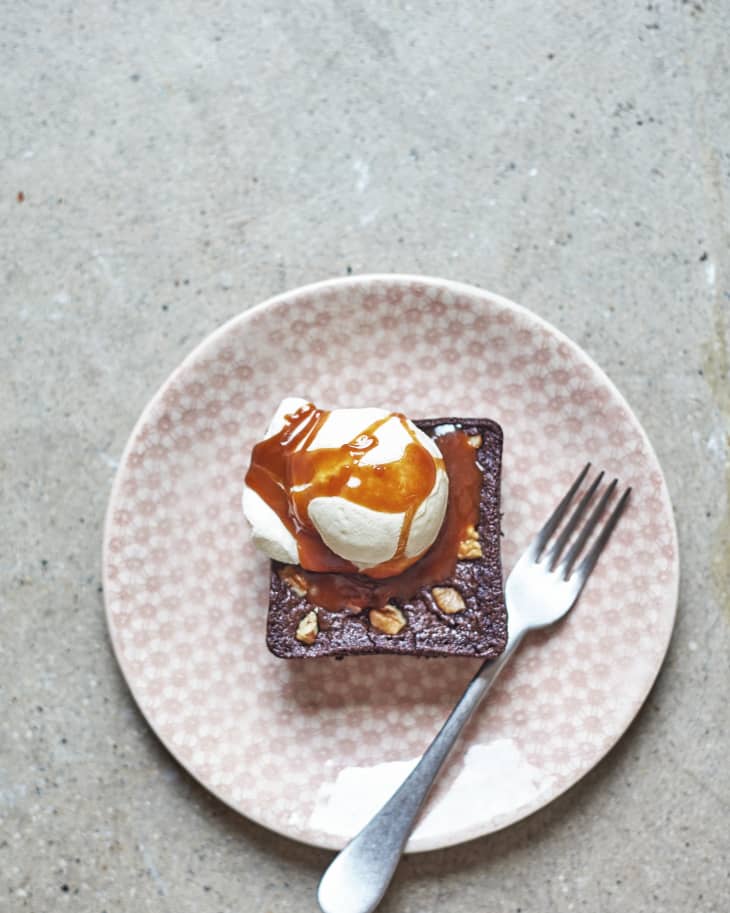 A square brownie served with vanilla ice cream and drizzled with caramel sauce on top