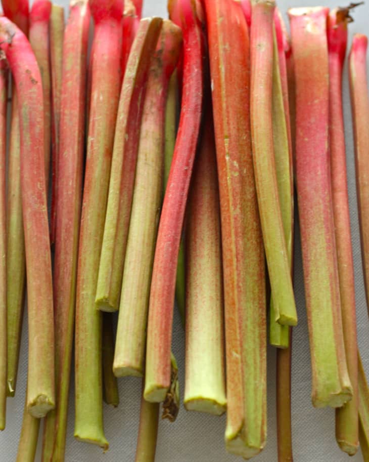 Fresh stalks of rhubarb, leaves removed, stacked lengthwise on a counter