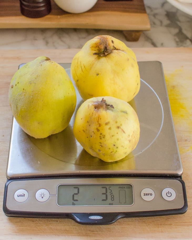 Three pieces of yellow-colored quince on a kitchen scale