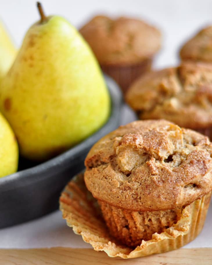 Baked spiced pear muffins are pictured with actual pear on the side