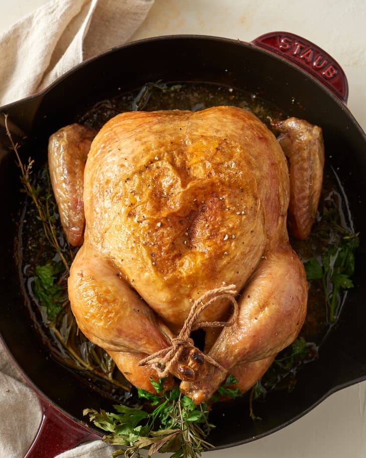 Golden-brown roasted chicken in cast iron pan.