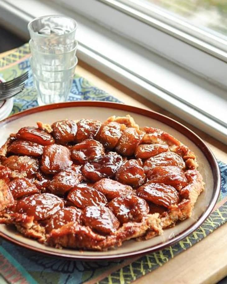 Tender apples in a deeply caramelized sauce over a buttery crust on a plate over a napkin