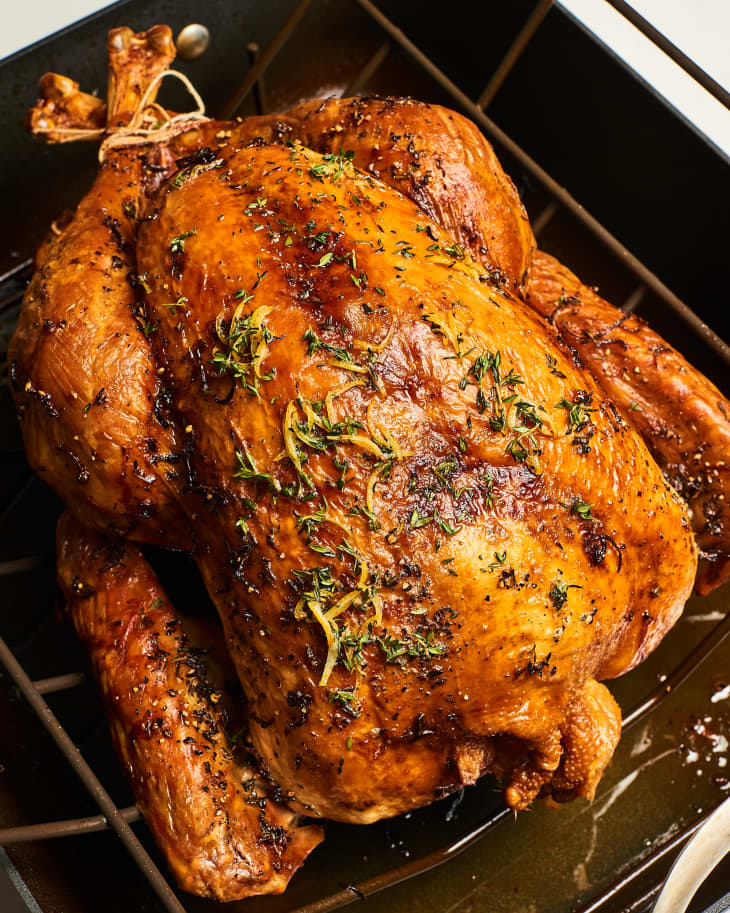 A roasted turkey with herbs in a roasting pan