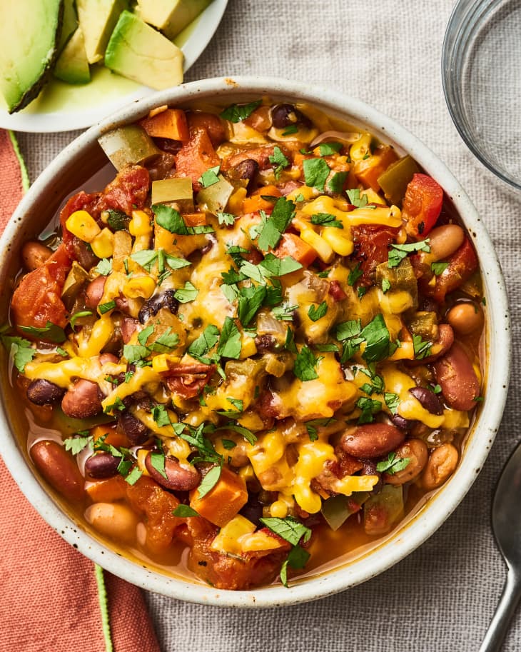 A bowl of vegetarian chili covered in melted cheese