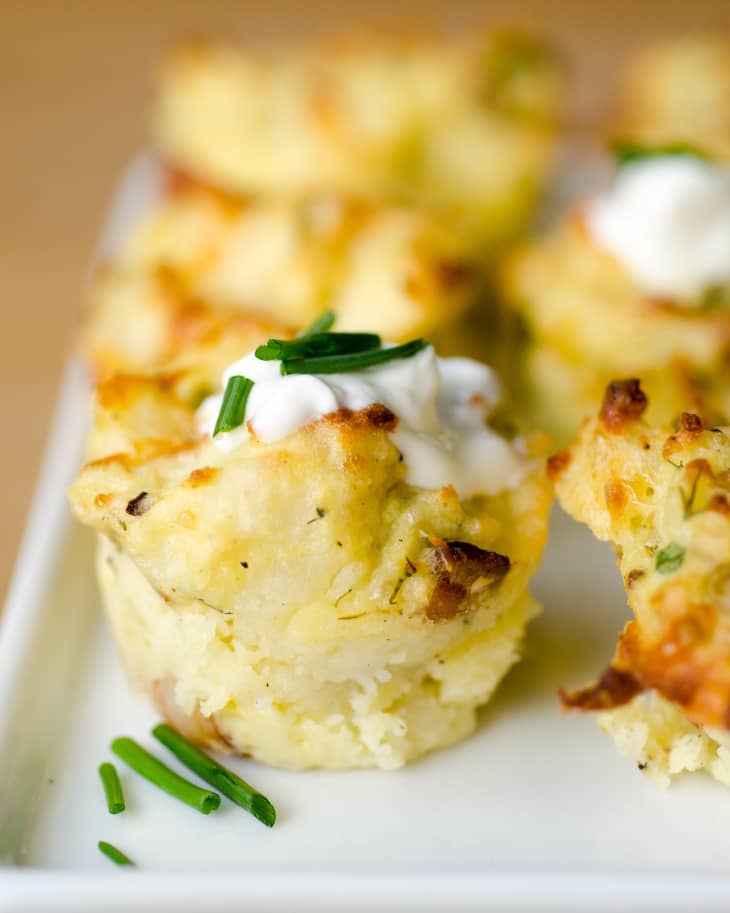 A close-up shot of cheesy mashed potato puffs, garnished with a little sour cream and chopped chives
