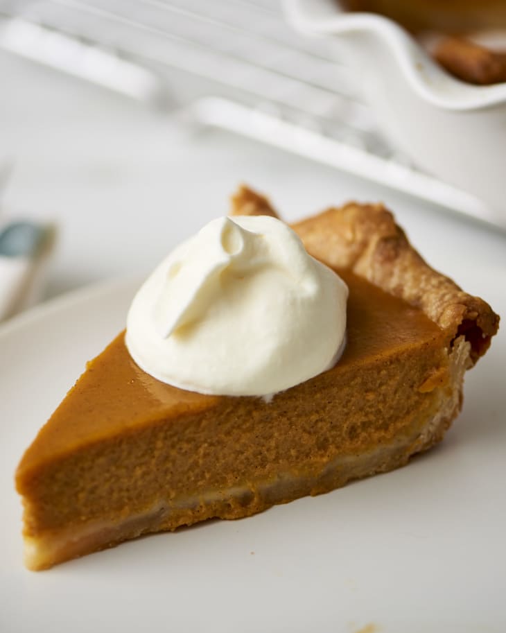 A single piece of pumpkin pie with a dollop of whipped cream on top