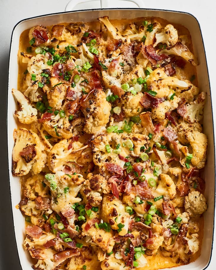 Baking dish filled with a cheesy cauliflower casserole with bacon bits and scallions