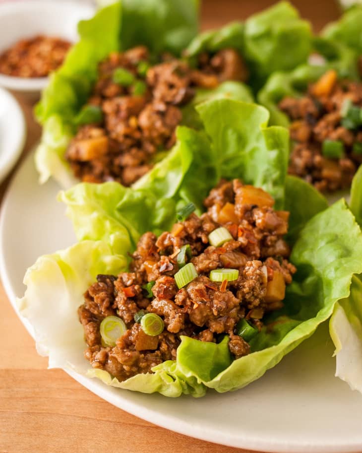 Chicken lettuce wraps, garnished with scallions, on a plate