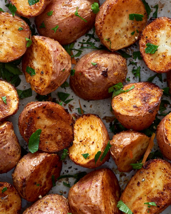 Roasted potatoes, garnished with chopped herbs, on a sheet pan