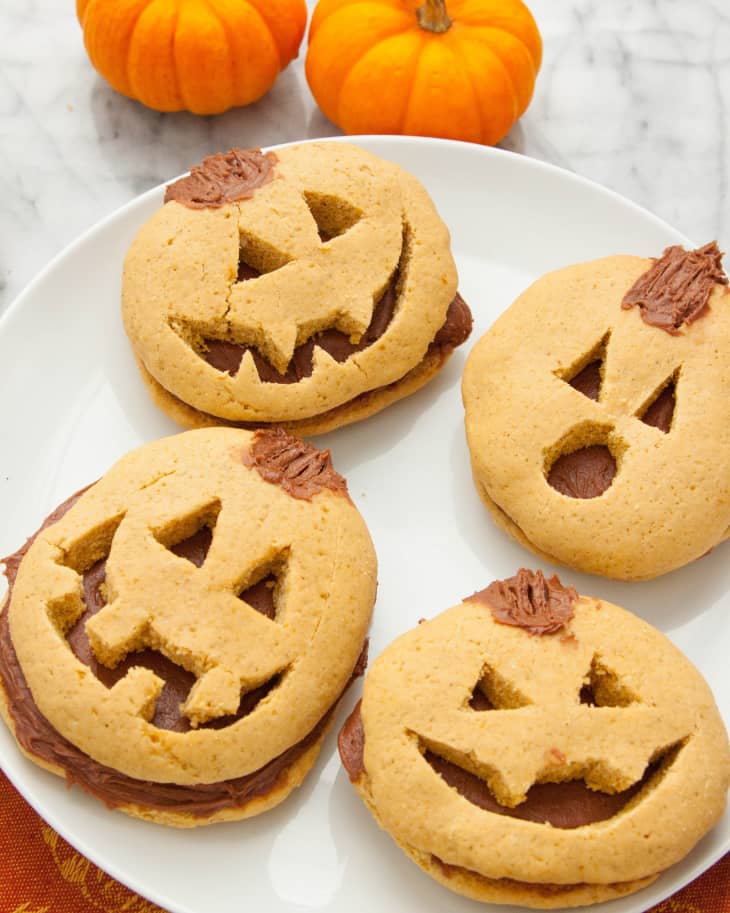 Image 2: Pumpkin-shaped cookies with chocolate filling on a white plate, surrounded by small pumpkins.