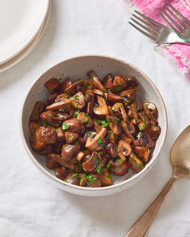 Bowl of stovetop-cooked mushrooms with chopped fresh parsley