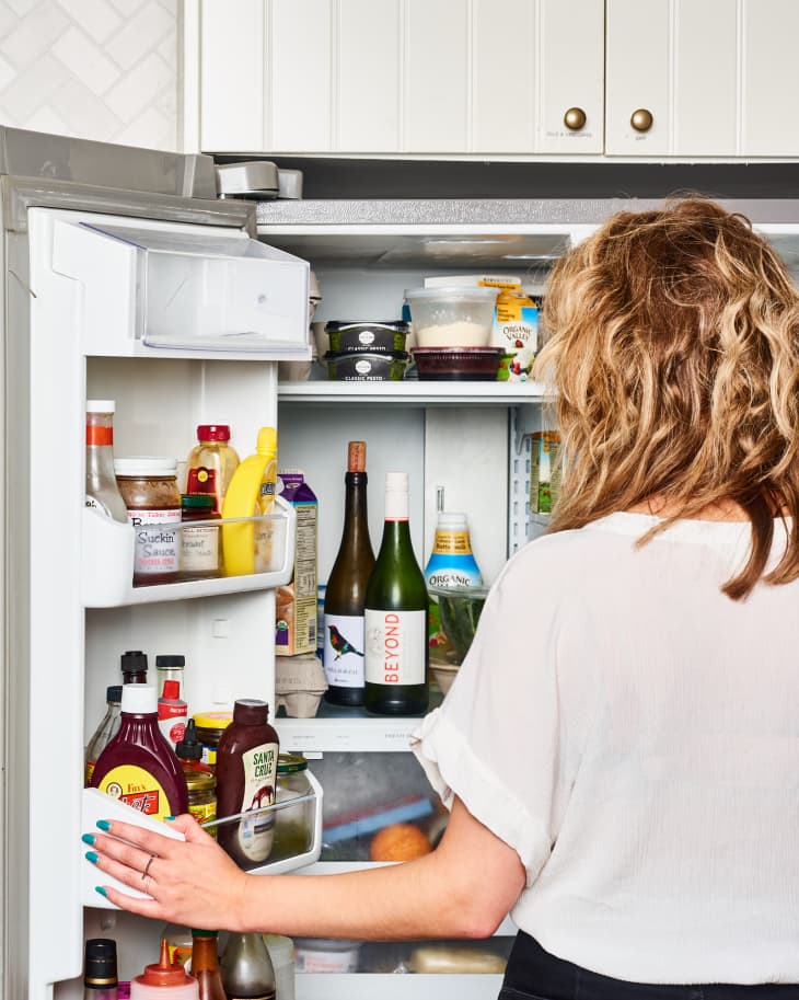 Person stands in front of the refrigerator door.